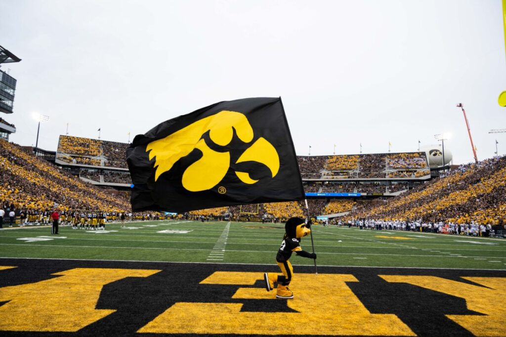 Iowa spirit squad member carrying tigerhawk flag across end zone at Kinnick Stadium