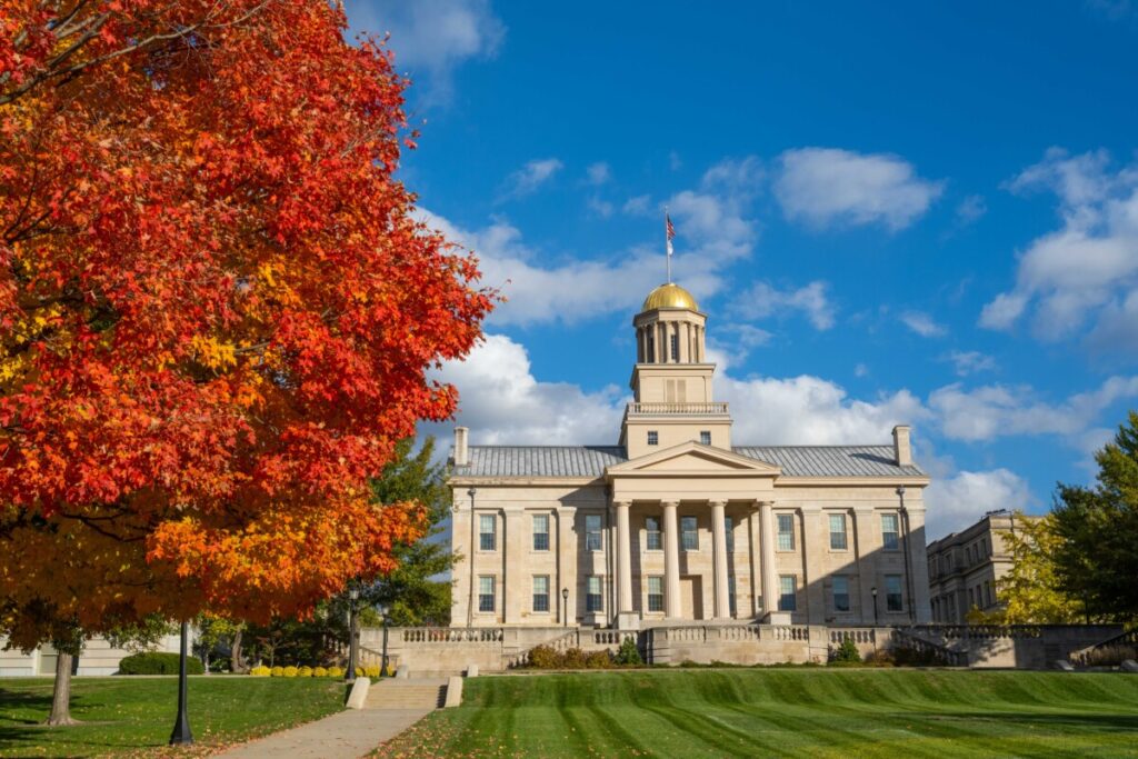 the Old Capitol building framed by a tree with bright orange/red leaves