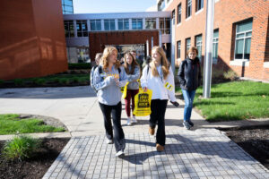 Students walking on campus with yellow bags.