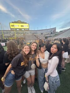 Four students at Kinnick smiling at the camera.