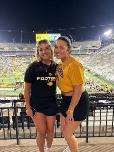 Two students smiling at the camera at Kinnick stadium in the evening.