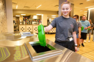 A student depositing an old to go box in the return bin.