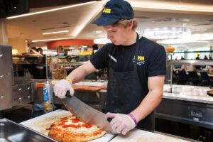 A chef cutting pizza into slices.