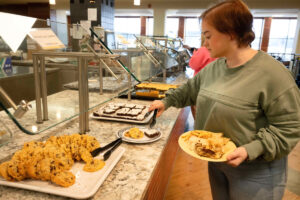 A student picking out a brownie from the dessert section.