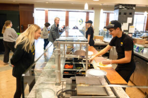 A student looking through the glass as the chef makes their food.