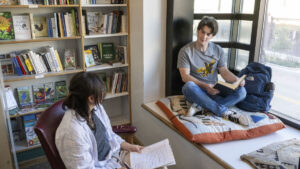 Two people sitting and chatting by a bay window.