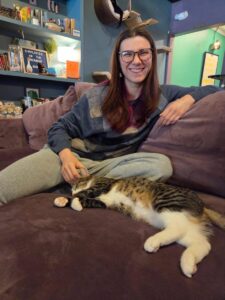 Kiah smiles at the camera while petting an adorable tabby cat named Carol.